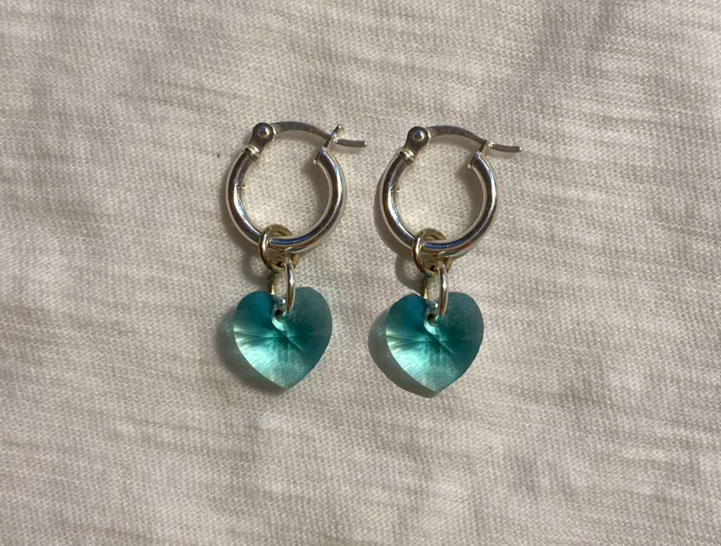 flat lay image of blue crystal heart earrings with sterling silver hoops