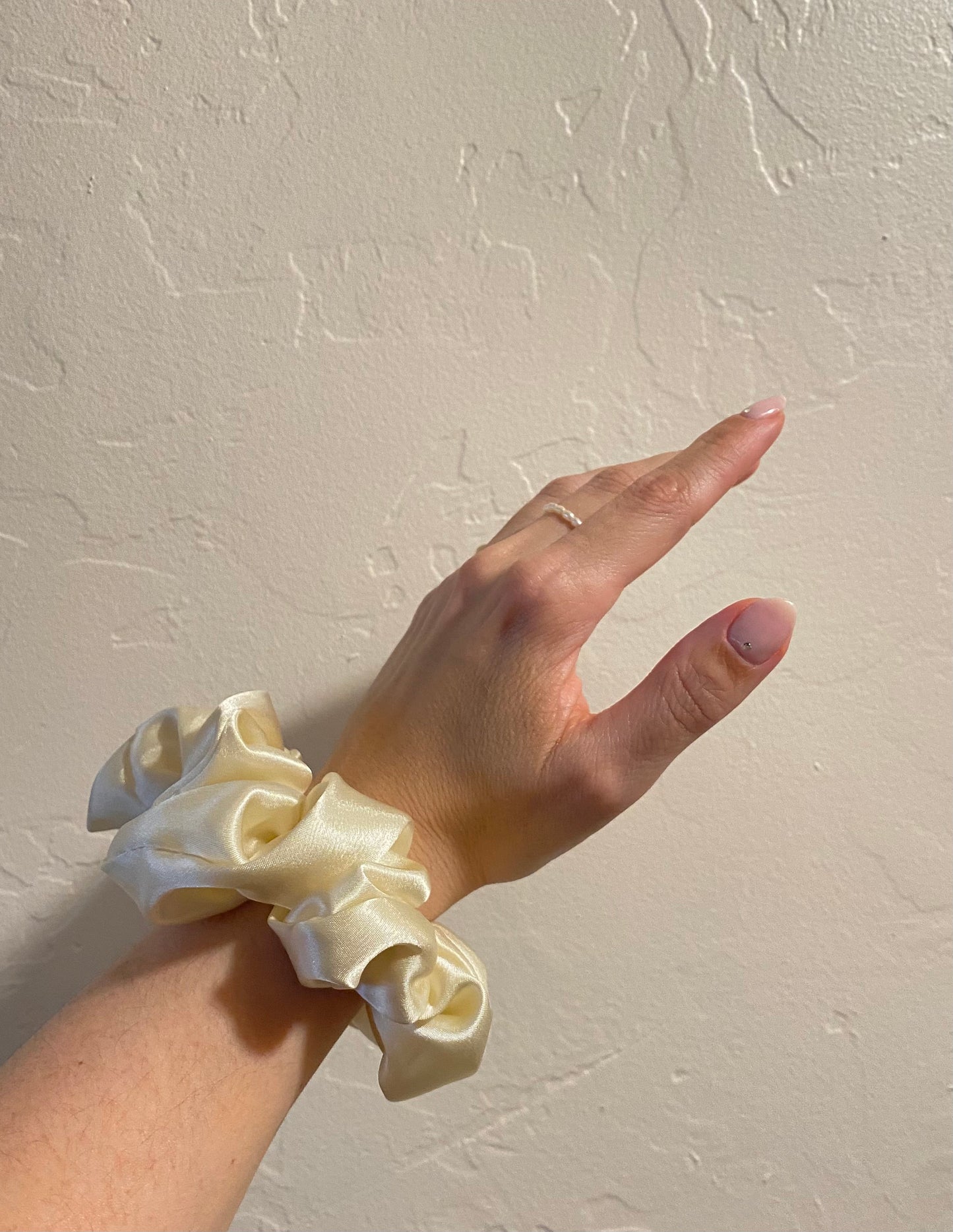 close up image, french vanilla satin scrunchie modeled on wrist