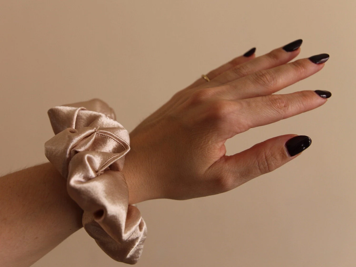 close up image, pink champagne scrunchie modeled on wrist.