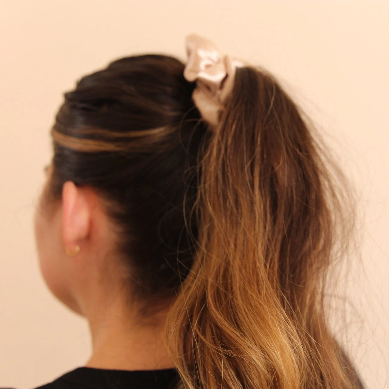 image of pink champagne scrunchie worn around a high ponytail. 